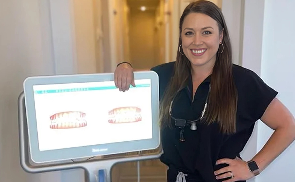 Dental professional displaying digital smile design mockups on tablet screen in modern office setting.