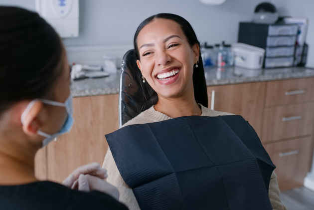 Smiling female dentist holding tablet speaking with male patient in modern dental office.