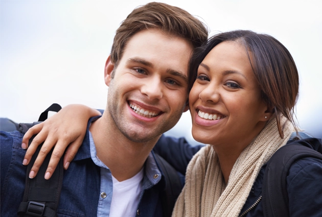 Two smiling people posing together outdoors with arms around each other against a light sky.