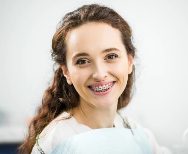 Young woman smiling at camera in white shirt, professional dental office setting